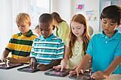 Children using tablets in a colorful classroom, highlighting technologys role in modern education.