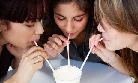 three girls enjoy a colorful drink, celebrating friendship and joy in a casual setting.