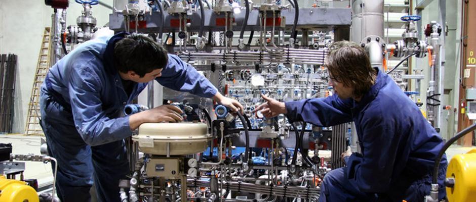 Technicians collaborating on complex machinery in a well-organized industrial facility.