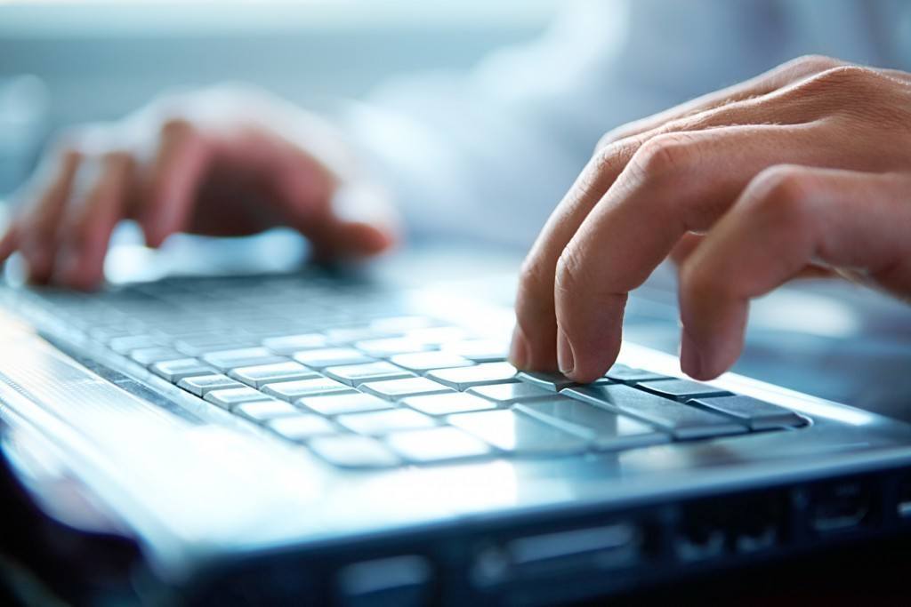 Hands typing on a laptop in a bright, organized workspace, symbolizing productivity and focus.