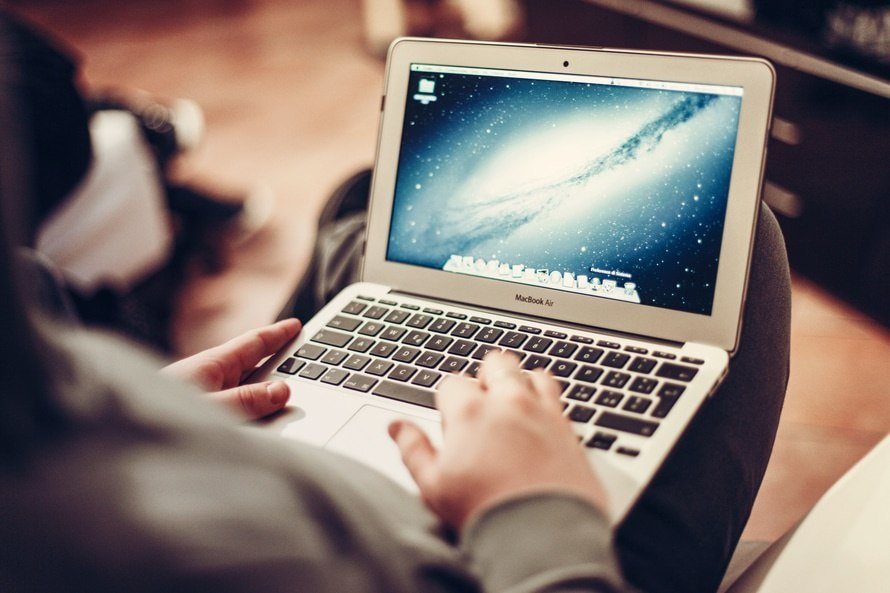 a relaxed individual uses a macbook air, enjoying technology in a cozy home setting.