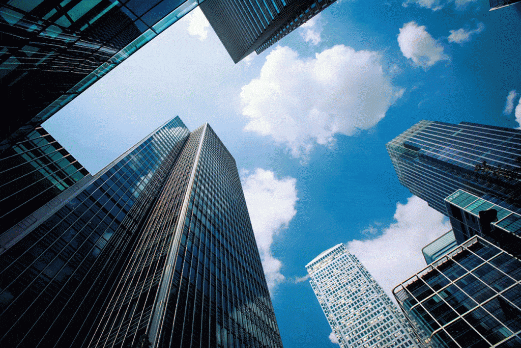 Modern skyscrapers reflect the blue sky, highlighting urban ambition and the blend of nature and architecture.