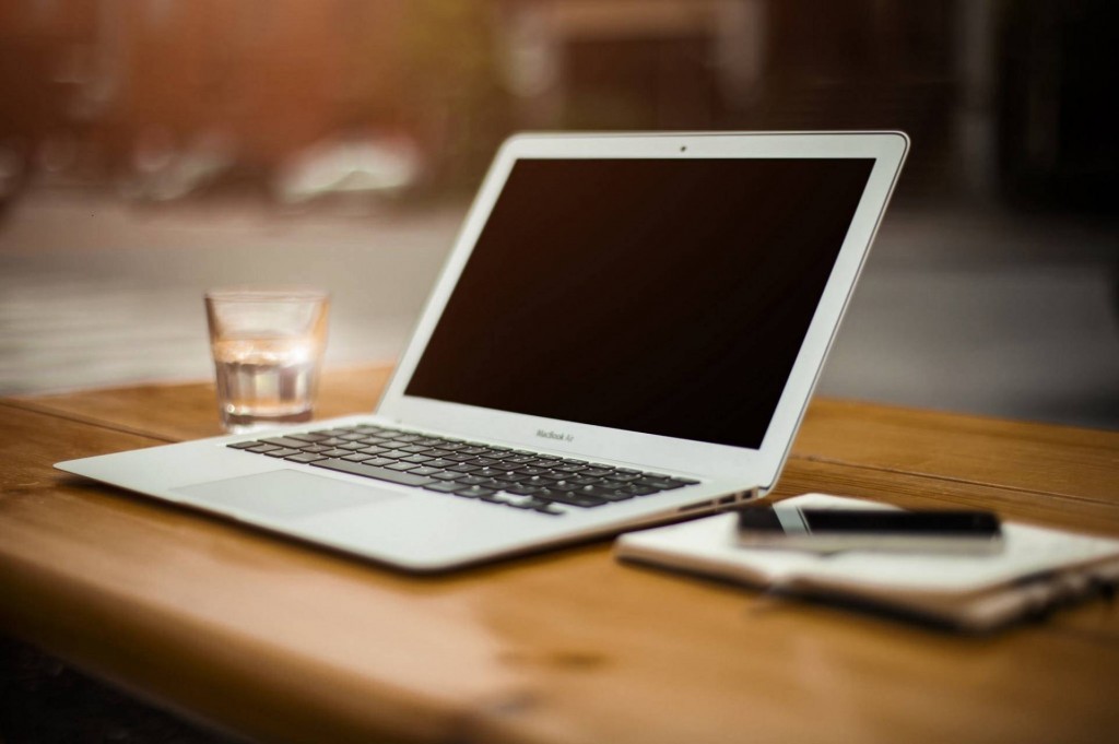 Cozy minimalist workspace featuring a MacBook, notebook, and glass of water for productivity.