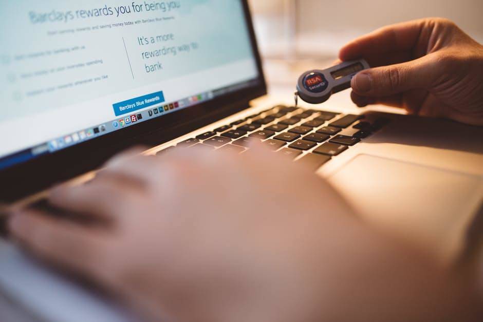 Person using a laptop for online banking, emphasizing security with a key fob.