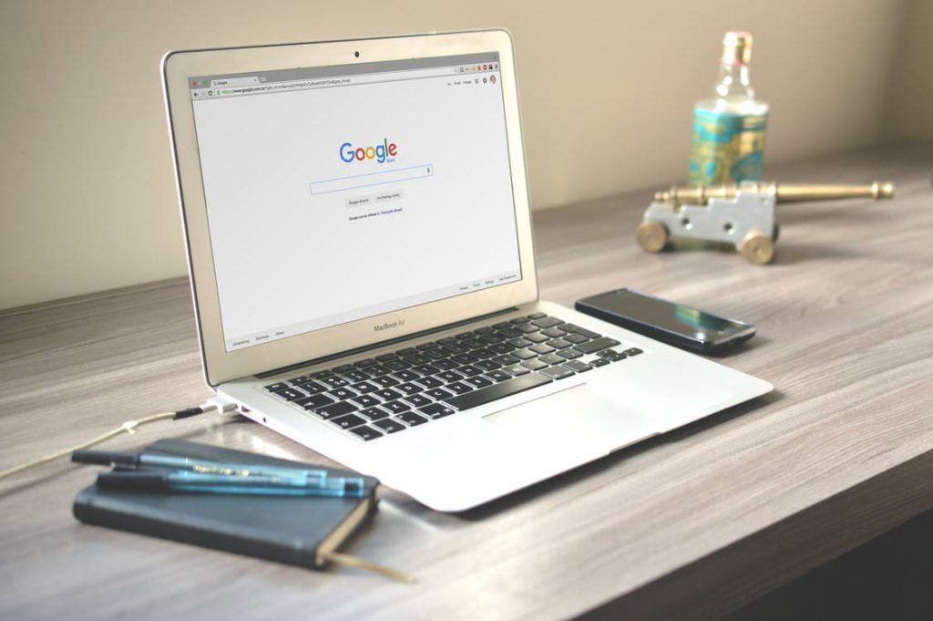 Minimalist workspace with MacBook Air, notebook, smartphone, and decorative elements for creativity.