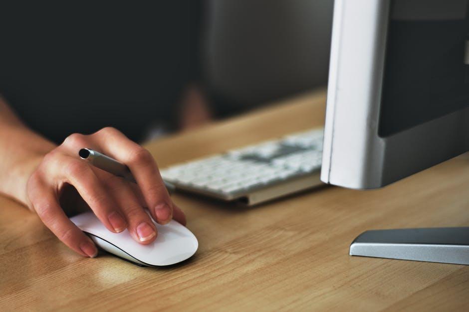 Focused hand using a sleek computer mouse in a modern, minimalist workspace.