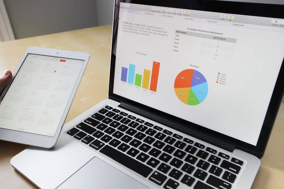 Modern workspace with laptop displaying data visuals and tablet for task management in natural light.