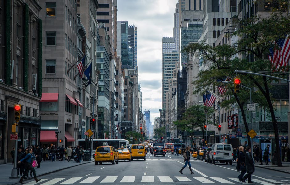 bustling city street with pedestrians and yellow taxis under an overcast sky, showcasing urban energy.