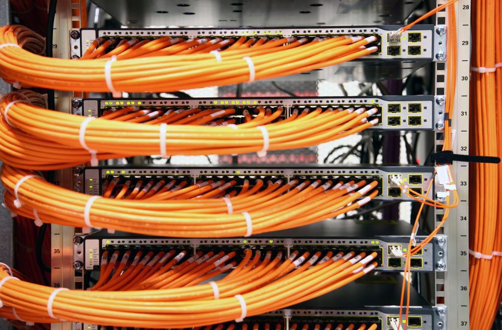 vibrant orange cables neatly organized in a server rack, showcasing efficient network infrastructure management.