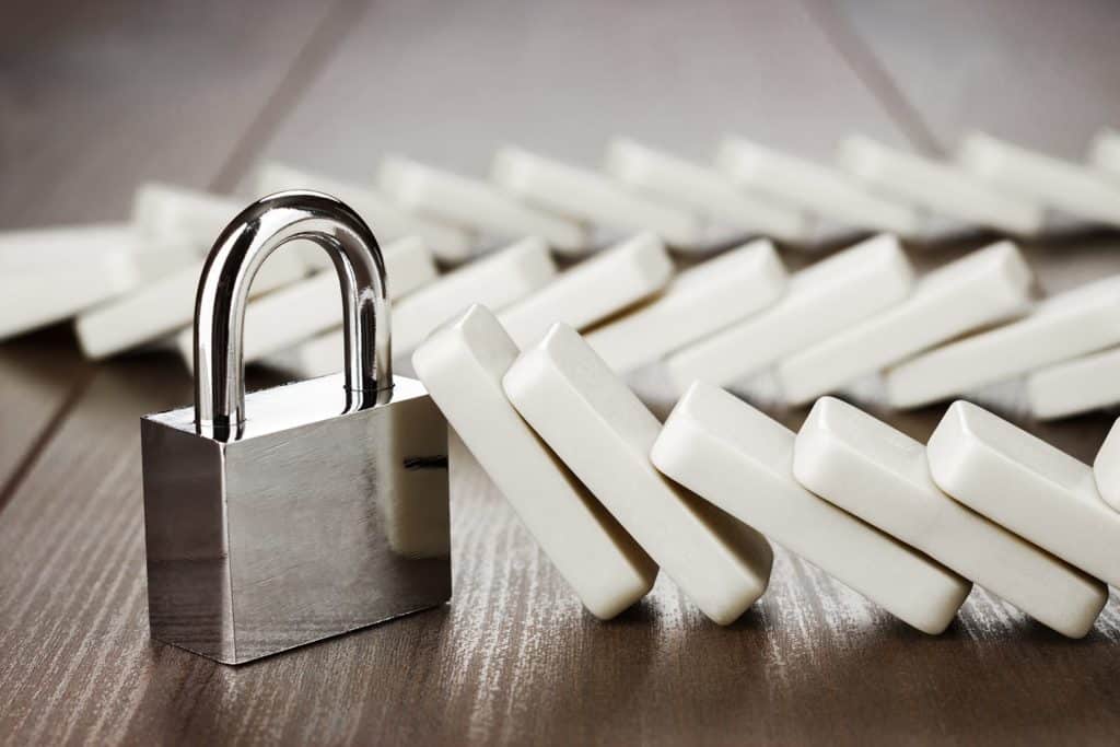 shiny padlock on wood with dominoes, symbolizing security and the tension of stability.