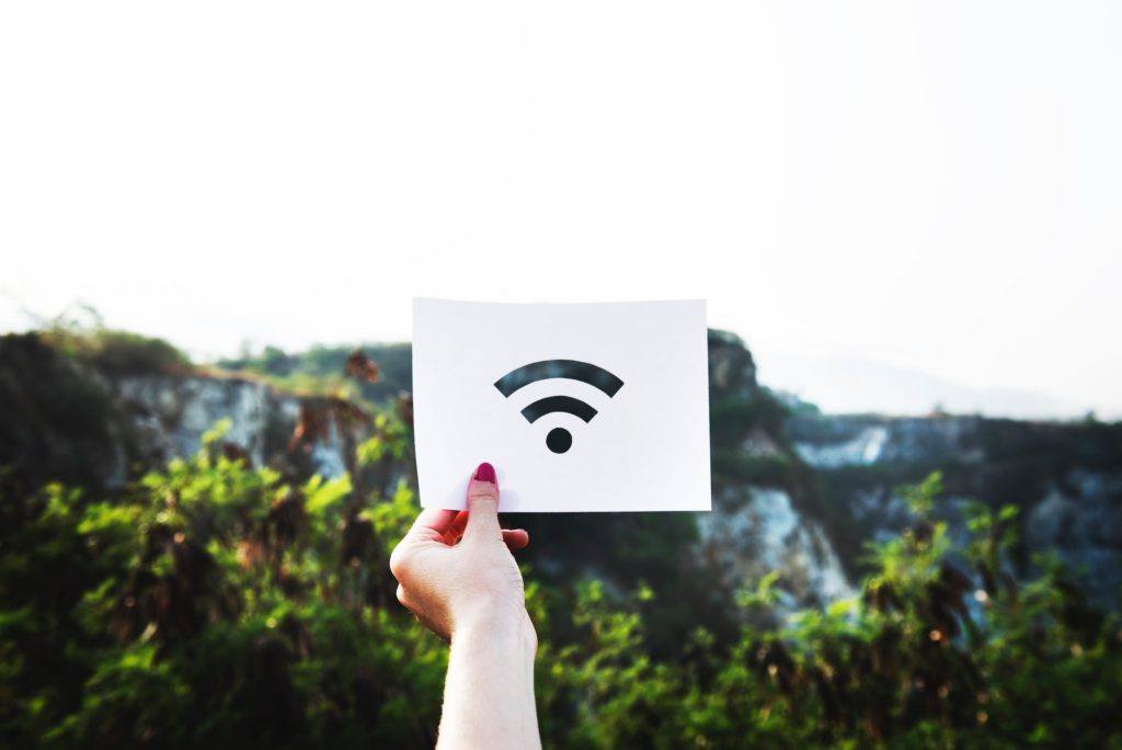 person displays a wi-fi symbol sign in a lush, natural landscape, blending technology with nature.