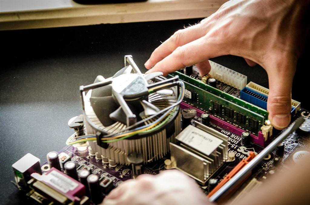 a close-up of a motherboard with a steady hand preparing to make precise adjustments.