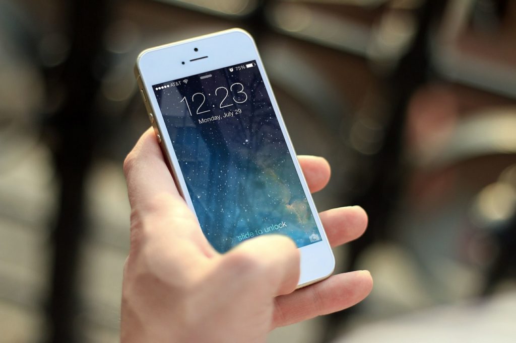 person holding a white iphone with a blurred background, showcasing modern smartphone connectivity.