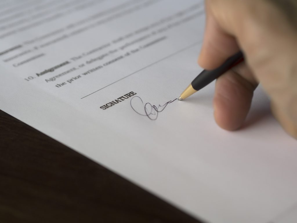 A hand poised with a pencil above a signature line, marking a moment of agreement.