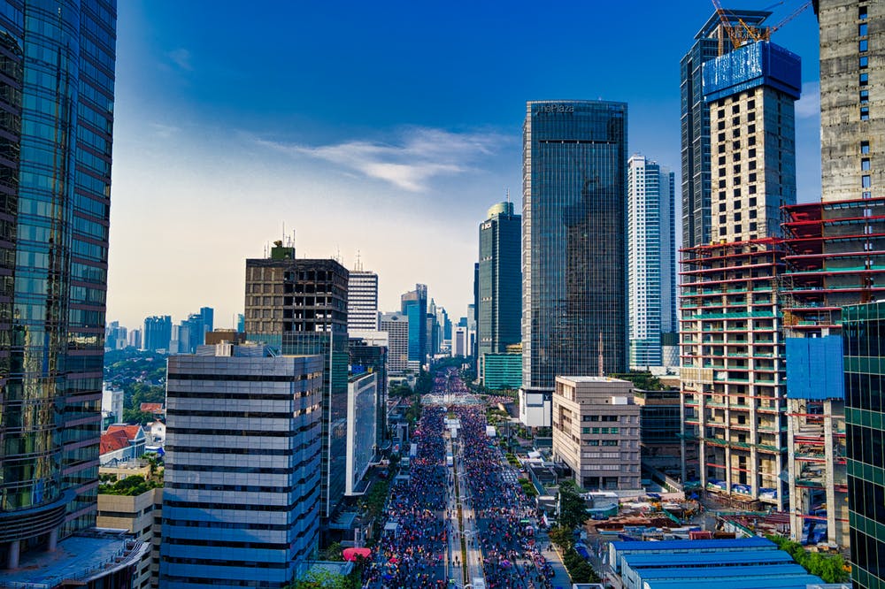 bustling city avenue with skyscrapers, vehicles, and vibrant urban life under a clear sky.