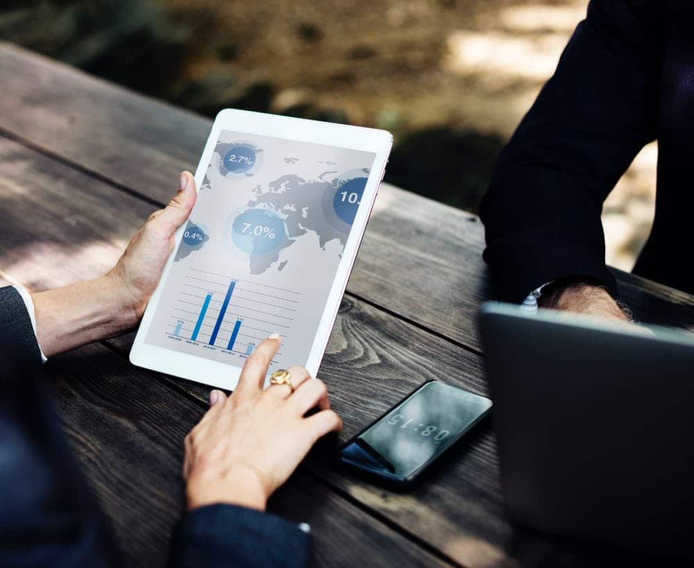 outdoor business meeting with data analysis on a tablet at a rustic wooden table.