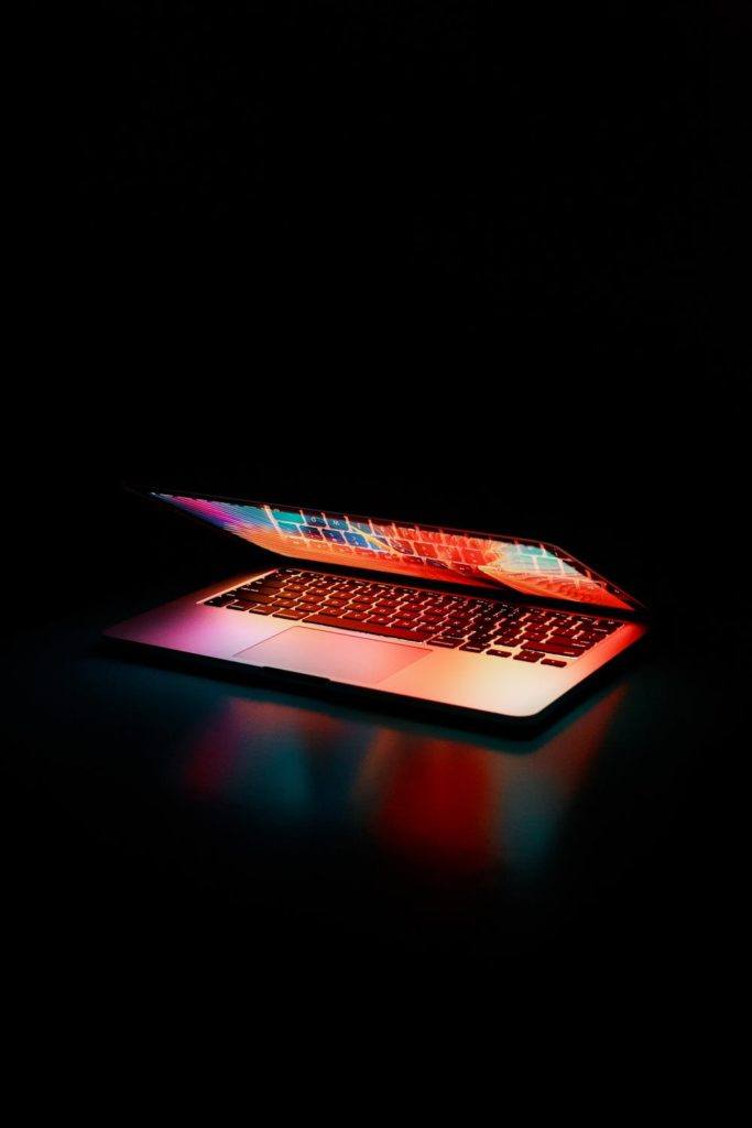 Sleek laptop glowing in low light, featuring a vibrant display and backlit keyboard.