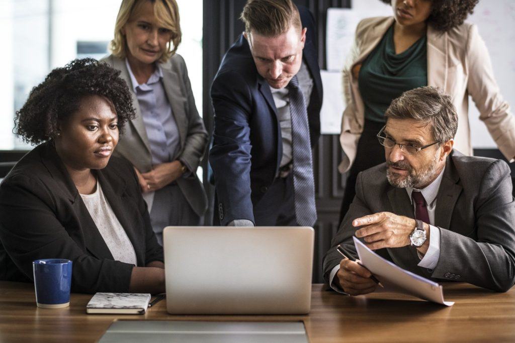 diverse professionals collaborate in a modern office meeting, focused on a digital presentation.