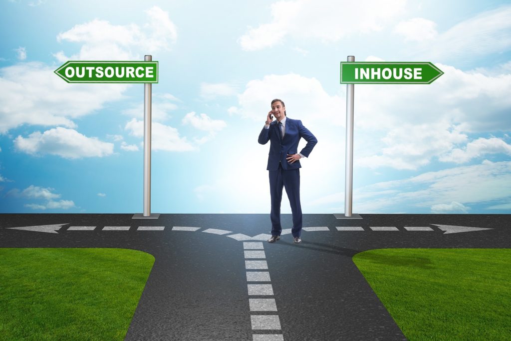 businessman at a crossroads, considering outsourcing versus in-house it support options.