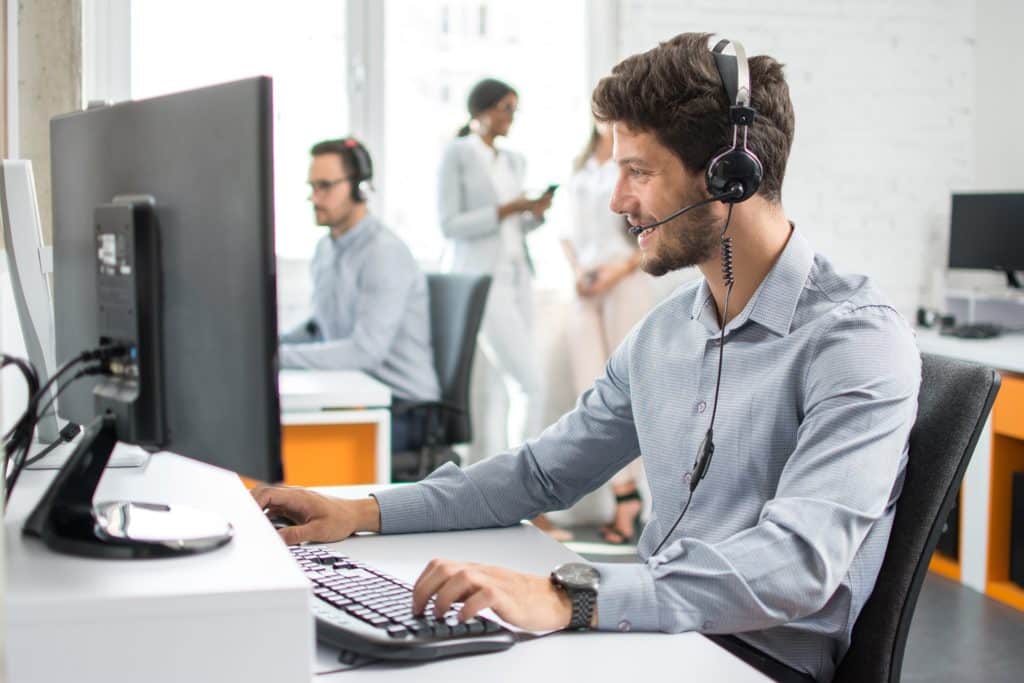 young man on a call in a bright, collaborative modern office setting.