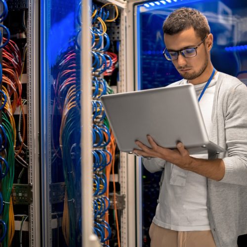 IT professional managing servers and network systems in a vibrant, high-tech environment.