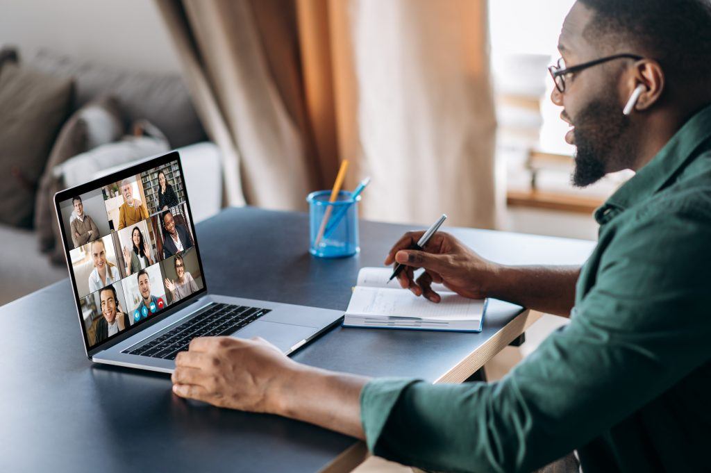 focused man in a home office engaged in a virtual meeting with diverse colleagues.