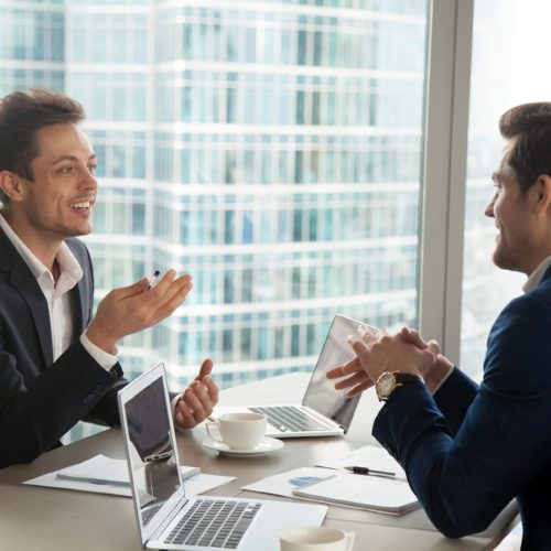 Young professionals discussing ideas in a modern office with a stunning city skyline view.