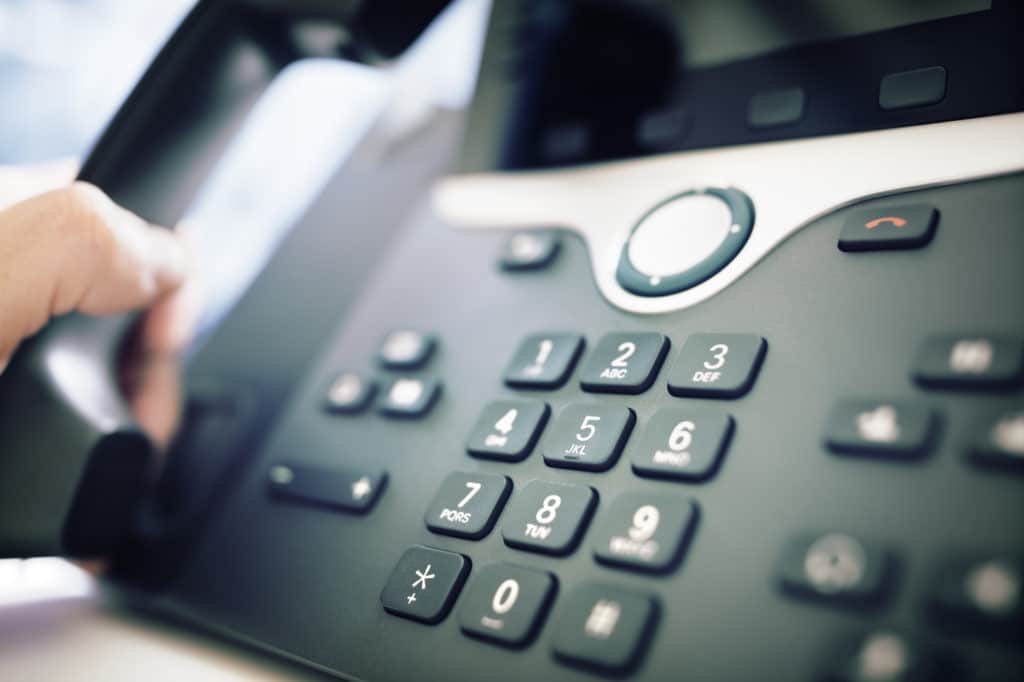 modern desk telephone close-up with hand poised to make a call, emphasizing communication readiness.