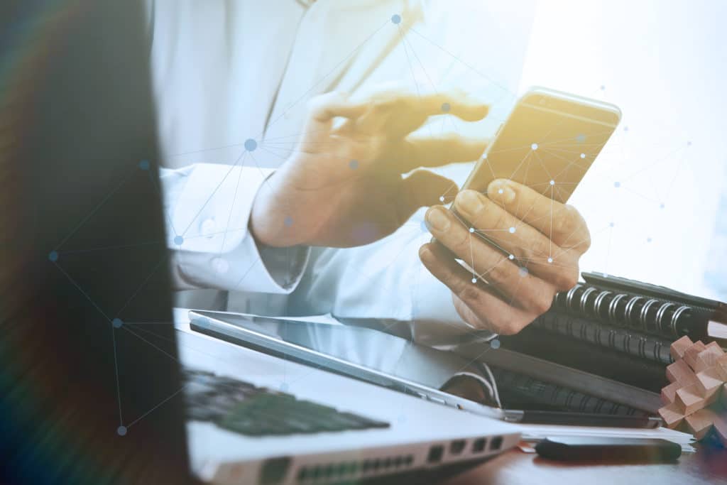 professional engaging with smartphone and laptop in a dynamic, organized workspace.