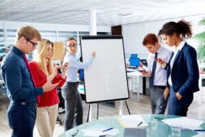 a group of people standing around a board in an office